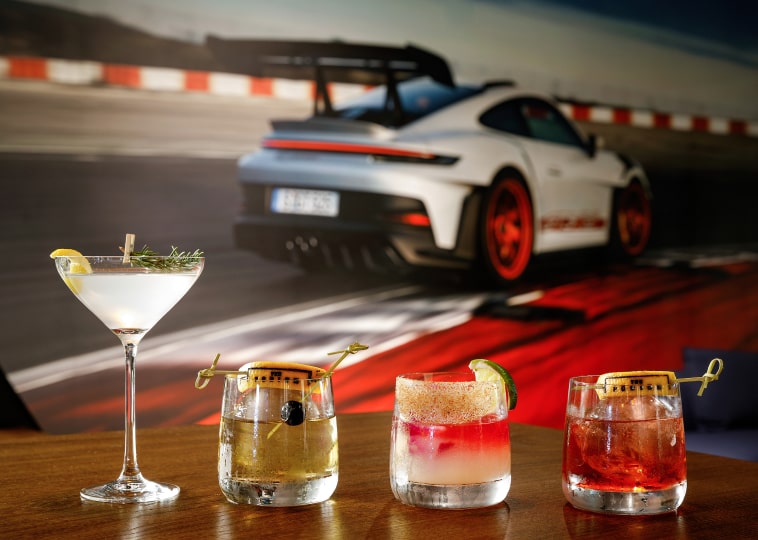 Closeup-up of four cocktails sitting on a table with car wall decor in the background