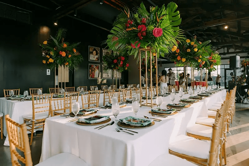 Interior of space featuring long tables fully set and decorated for an event