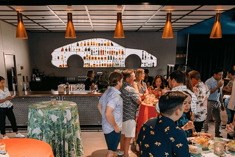 Group of people smiling and talking in front of cocktail bar